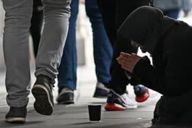 A person kneeling on the pavement begs for money on The Strand in central London on October 1, 2022, as campaigners gather in the city to protest against the cost of living crisis. (Photo by Justin TALLIS / AFP) (Photo by JUSTIN TALLIS/AFP via Getty Images)