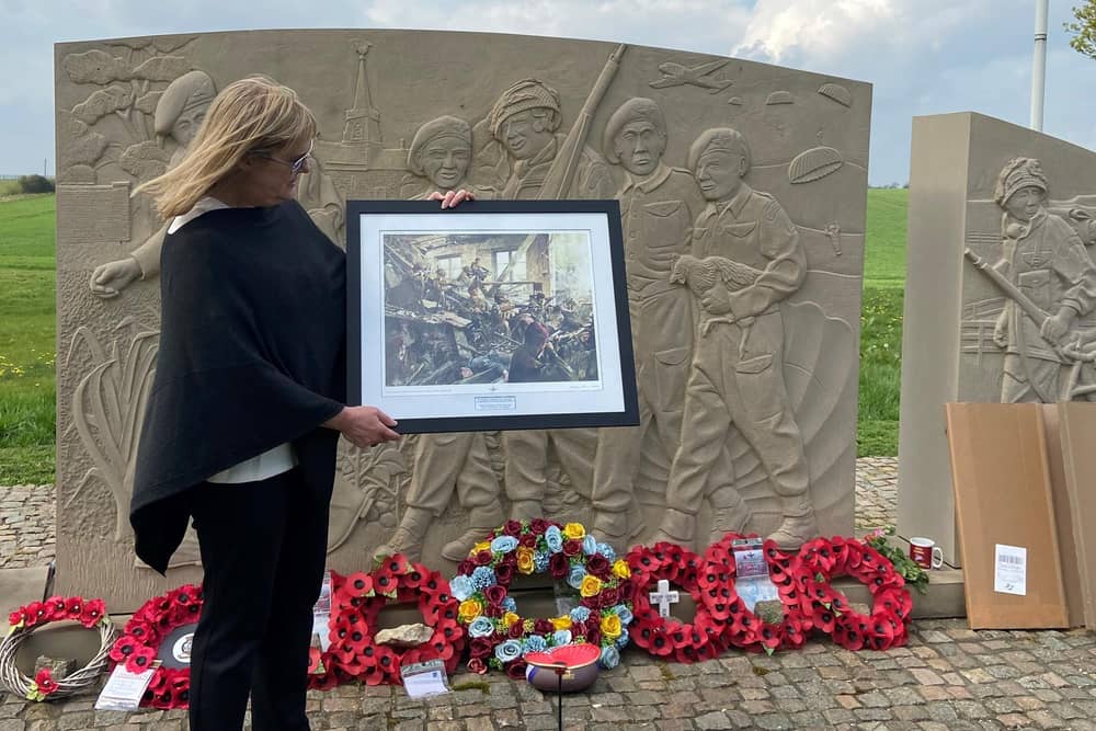 Laura Briggs holds a framed print of Derek Chambers' ‘The Last Stand', presented to her by FOTT chairman Alec Wilson at the 10th Battalion Memorial at Burrough-on-the-Hill