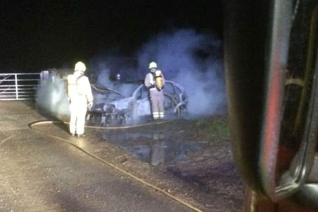 Two Melton firefighters wearing breathing apparatus tackle a blazing car which was set alight on Sandy Lane in the town EMN-180801-105054001