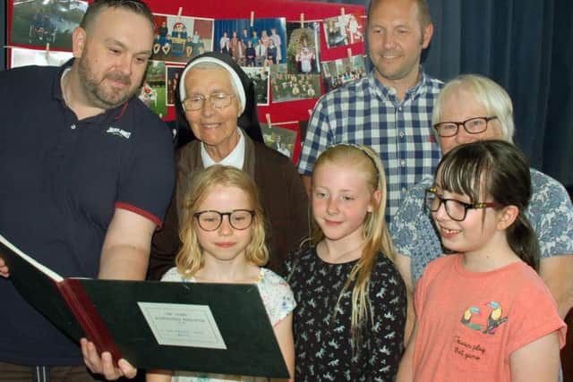 St Francis Catholic Primary School pupils past and present look at an old school register with Sister Anthony, who was a teacher there from 1956 to 1996 EMN-180626-154425001