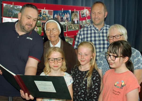 St Francis Catholic Primary School pupils past and present look at an old school register with Sister Anthony, who was a teacher there from 1956 to 1996 EMN-180626-154425001