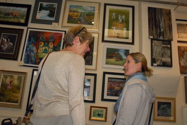 Rosemary Russell (left) discusses the artwork on show at the village hall exhibition PHOTO: Tim Williams