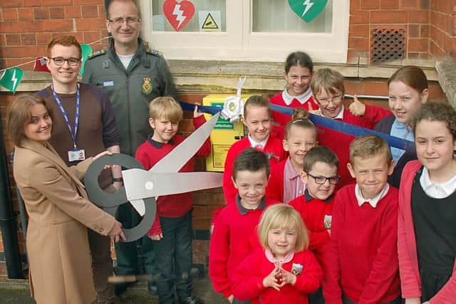 New defibrillators are unveiled at Asfordby Hill Primary School by head teacher Tracy McConnell cuts the ribbon with Ben Ryrie from EMAS and pupils from the school council EMN-190118-143711001