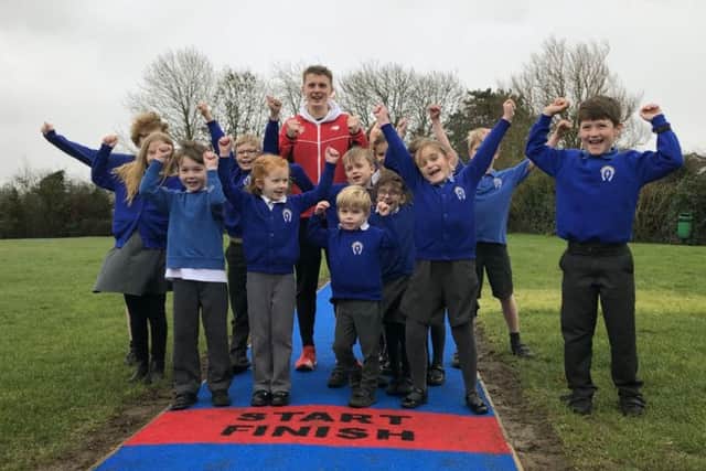 GB athlete Ben Higgins with pupils of Whissendine Primary School as he launched its new Daily Mile track EMN-190802-121729001