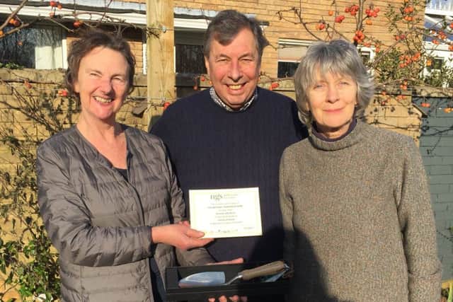 Rose Dejardin - who is stepping down after many years as county organiser - presenting, on behalf of the National Garden Scheme, an engraved trowel to David and Jeffy Wood who have opened their garden at Townsend House, Wing for ten years PHOTO: Supplied