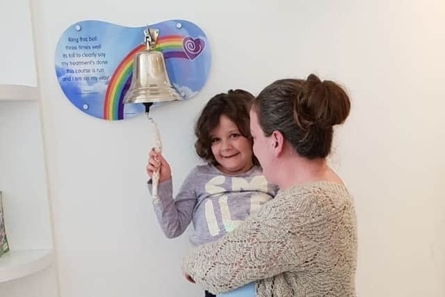 Evie Moore, with mum Helena Isaac, rings the bell at Sheffield Children's Hospital to celebrate being given the all-clear from leukaemia EMN-191021-150553001