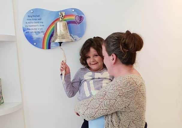 Evie Moore, with mum Helena Isaac, rings the bell at Sheffield Children's Hospital to celebrate being given the all-clear from leukaemia EMN-191021-150553001