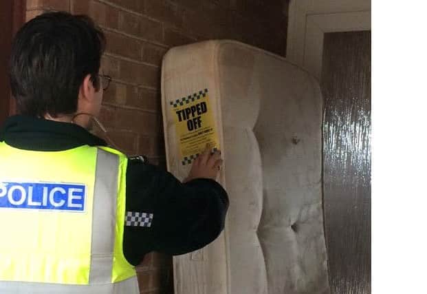 A police officer attaches a fly-tipping notice to a dumped mattress EMN-160120-130309001