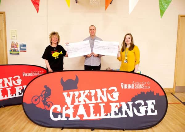 Colin Shearer, chairperson of the Viking Challenge Committee, presents Redmile headteacher Julie Hopkins (left), and Charlotte Marson from the Derbyshire, Leicestershire and Rutland Air Ambulance, with their cheques 
PHOTO: Supplied