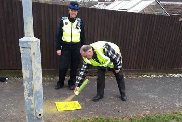 Melton resident and dog patrol volunteer Frank Duckworth highlights a dog fouling hotspot in the Grange Drive area using his temporary spray paint and stencil, watched by a Melton police officer EMN-160329-175812001