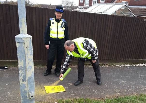 Melton resident and dog patrol volunteer Frank Duckworth highlights a dog fouling hotspot in the Grange Drive area using his temporary spray paint and stencil, watched by a Melton police officer EMN-160329-174546001 EMN-160329-174546001