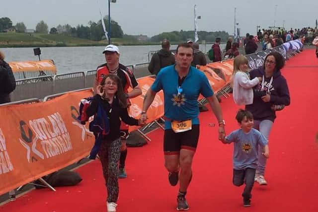 Mark crossing the finish line of his triathlon with his family
PHOTO: Supplied