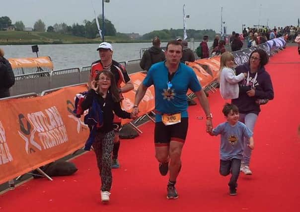 Mark crossing the finish line of his triathlon with his family 
PHOTO: Supplied