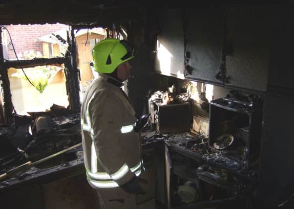 Firefighter Nick Spargo inspects the damage in Mr Bielski's kitchen following the blaze EMN-160620-111033001