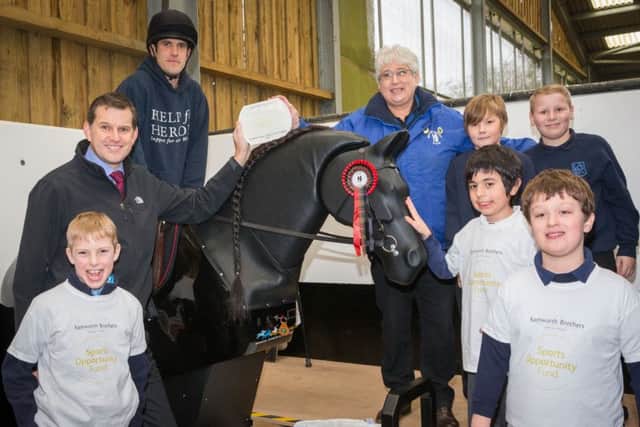 Joseph Platt rides Jet, the new mechanical horse at The Mount Group riding school for the disabled at Somerby, with Samworth Brothers Sports Opportunity Fund trustee Tim Barker (left), Mount Group trustee Pat Bishop and children from Knossington Grange School and Oakham CE Primary Schooll EMN-160825-135339002