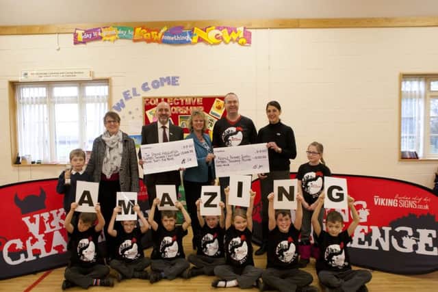 Colin Shearer, chairperson of the Viking Challenge Committee (2nd from right), presents Redmile head teacher Julie Hopkins (centre), and Paul Lawless and Louise Knight (right) members of the Stroke Association, with their cheques. Also pictured are children from Redmile School and Helen Snow (2nd from left), for the Peter Snow Award which was awarded to Mark Beeston. His son Max accepted on his father's behalf PHOTO: Supplied