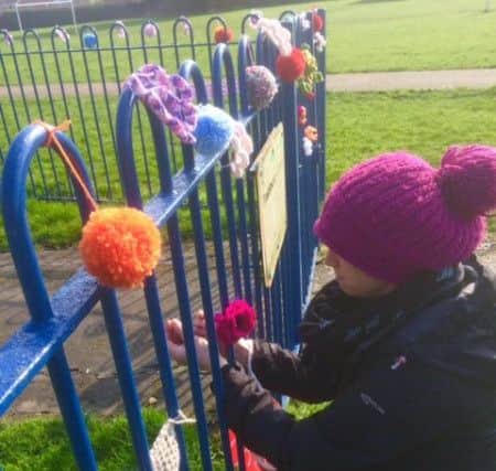 Jo Frederick attaching woollen items to the play area's railings PHOTO: Supplied