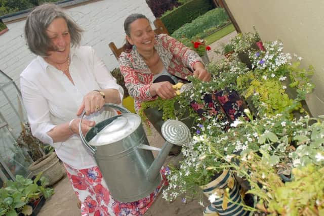 Alison Blythe and gardener Christina Moulton tend to some ornamental welly boots at the open garden event PHOTO: Tim Williams