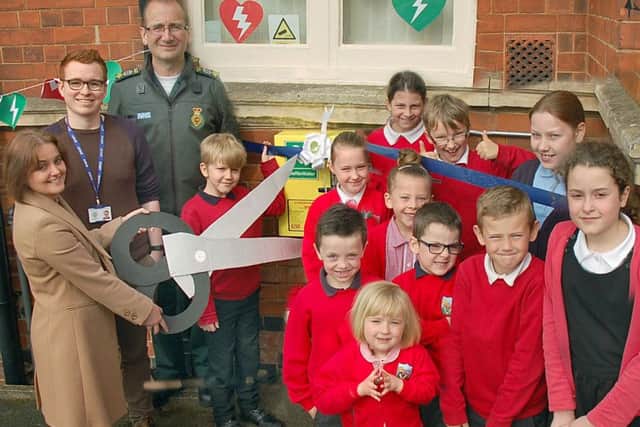 New defibrillators are unveiled at Asfordby Hill Primary School by head teacher Tracy McConnell cuts the ribbon with Ben Ryrie from EMAS and pupils from the school council EMN-170205-114211001