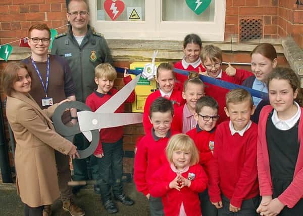 New defibrillators are unveiled at Asfordby Hill Primary School by head teacher Tracy McConnell cuts the ribbon with Ben Ryrie from EMAS and pupils from the school council EMN-170205-114211001
