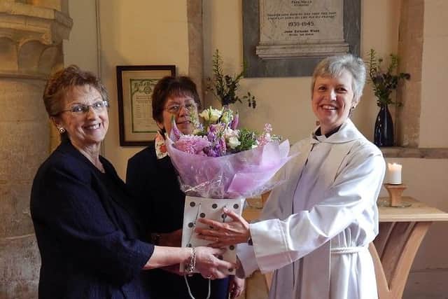 Rev Dr Mary Barr is presented with some flowers as a welcome gift by St James churchwarden Jenny Pengelly, left, watched by fellow churchwarden Janet King PHOTO: Supplied