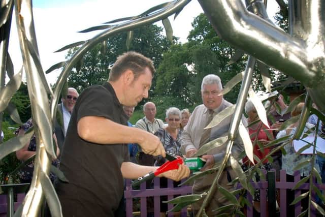 Liam McCallion attaches dedicated leaves to a stainless steel willow tree in the new sensory garden at the Melton elderly housing complex EMN-170506-102921001