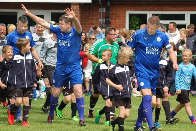 Gerry Taggart and Steve Walsh lead the Leicester City FC legends out with members of Asfordby FC juniors at the start of Sunday's charity match EMN-170613-180728001
