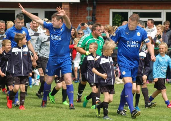 Gerry Taggart and Steve Walsh lead the Leicester City FC legends  out with members of Asfordby FC juniors at the start of Sunday's charity match EMN-170613-180728001