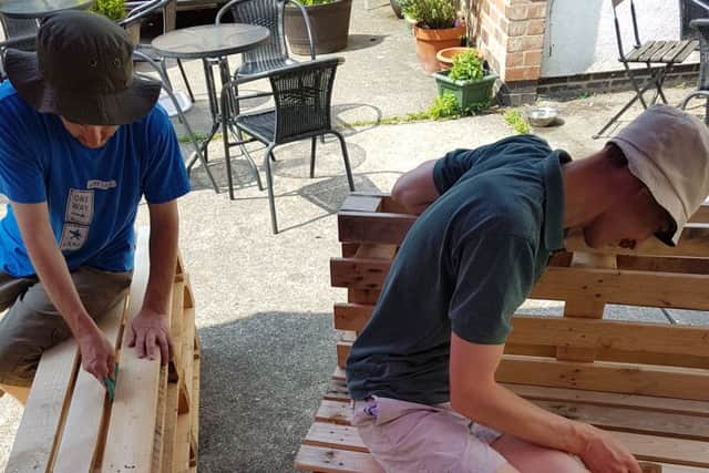 Volunteers from The Lodge Trust sand down benches at Melton's More Coffee Co PHOTO: Supplied