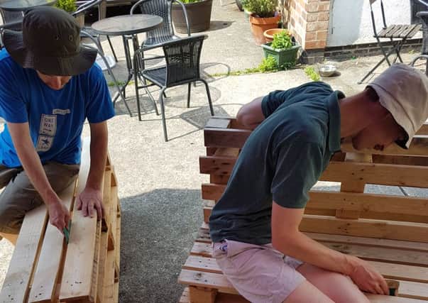 Volunteers from The Lodge Trust sand down benches at Melton's More Coffee Co PHOTO: Supplied