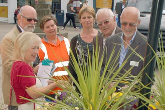 Members of Melton in Bloom, Melton Bid and the East Midlands in Bloom judges look at one of the themed planters in Market Place, Melton EMN-170507-114555001