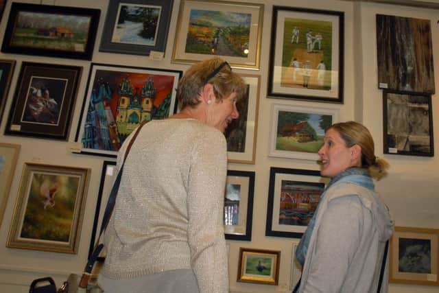 Rosemary Russell (left) discusses the artwork on show at the village hall exhibition PHOTO: Tim Williams