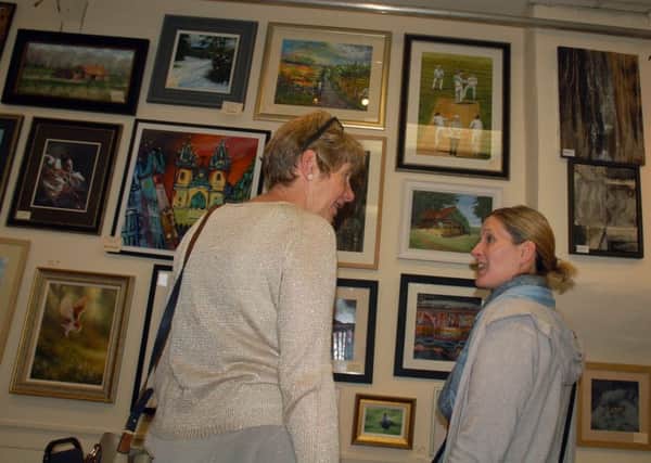 Rosemary Russell (left) discusses the artwork on show at the village hall exhibition PHOTO: Tim Williams